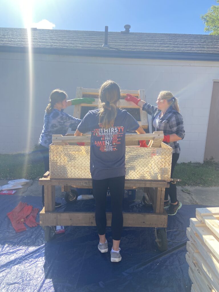 Three volunteers work on building a headboard.