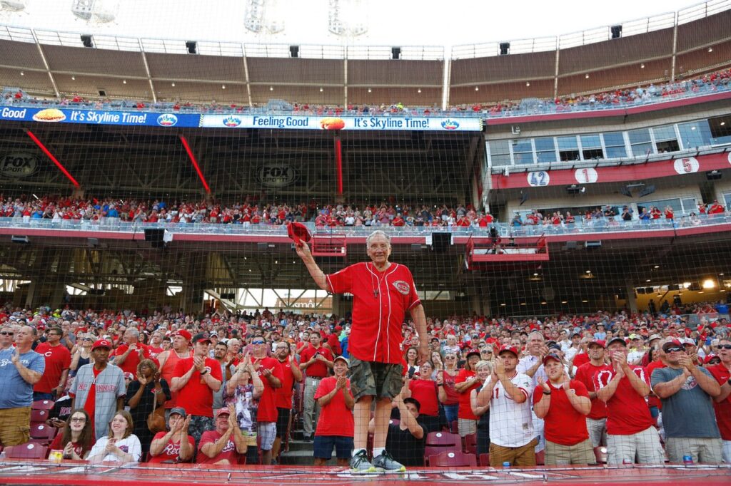Don Petersman walks out onto the dugout during a Cincinatti Reds game as the crowd cheers for him.
